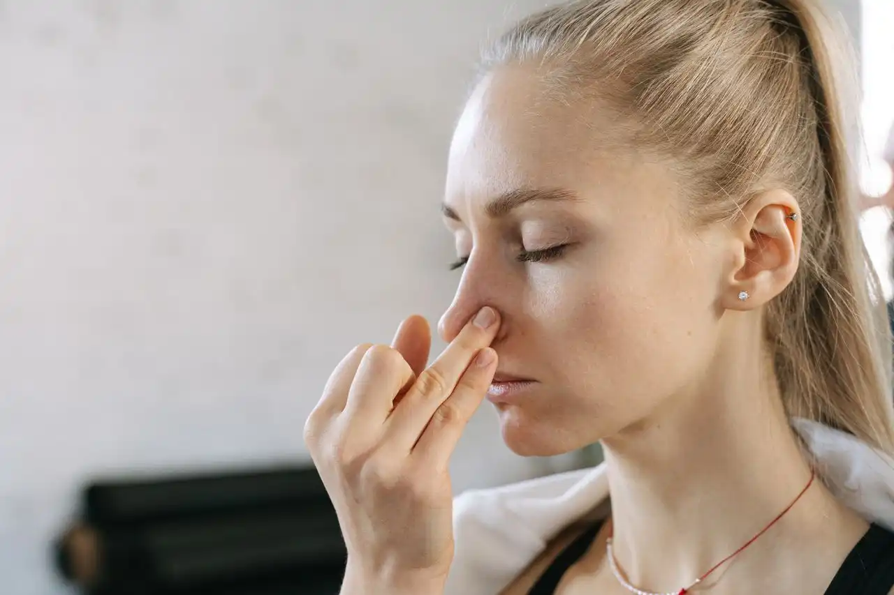 A woman with her eyes closed pinching the bridge of her nose